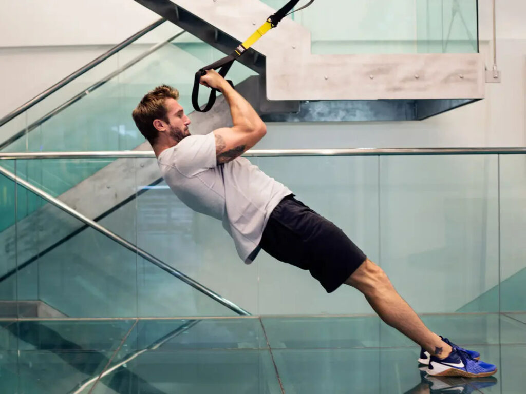 a male fitness influencer practicing TRX